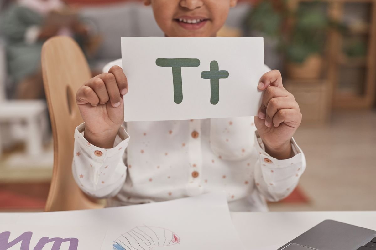 Niña mostrando una tarjeta con letras en terapia de lenguaje